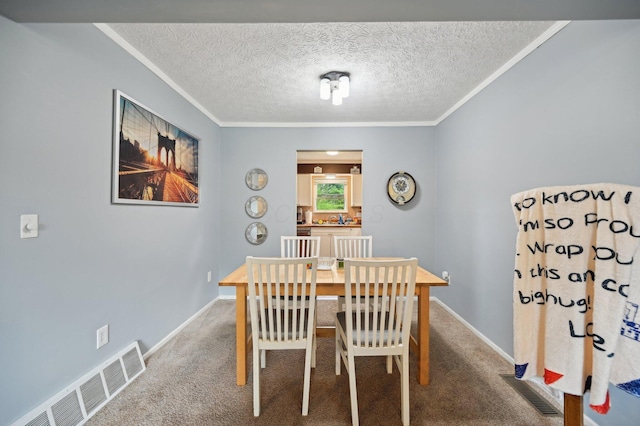 dining room with visible vents, a textured ceiling, crown molding, and carpet floors