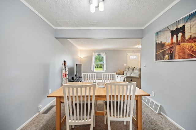 dining room featuring ornamental molding, carpet flooring, a textured ceiling, and visible vents