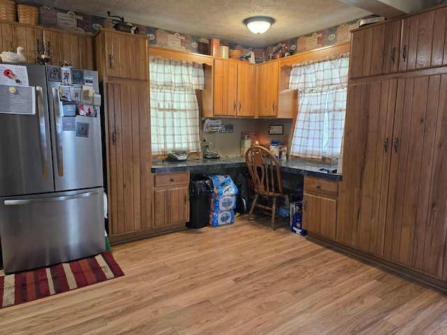 kitchen featuring dark countertops, built in desk, light wood-style floors, and freestanding refrigerator