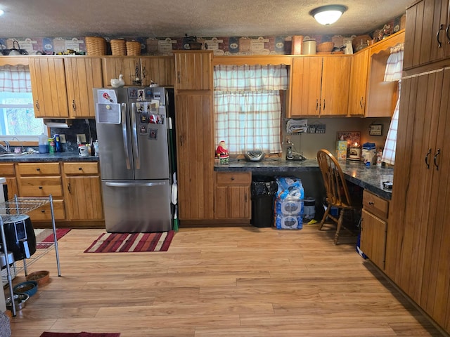 kitchen featuring freestanding refrigerator, dark countertops, built in study area, and a textured ceiling