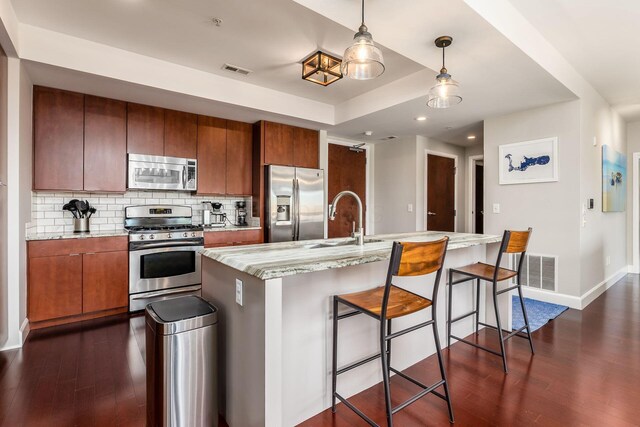 kitchen with brown cabinets, stainless steel appliances, dark wood-style floors, and a sink