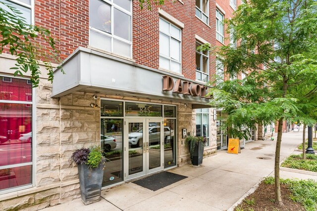 entrance to property featuring brick siding, french doors, and stone siding