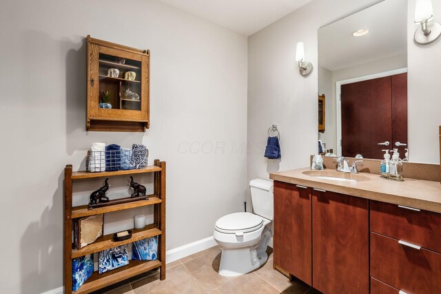 half bathroom featuring toilet, baseboards, tile patterned flooring, and vanity