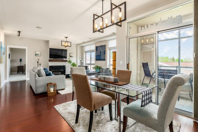 dining area featuring a chandelier, dark wood finished floors, and a fireplace