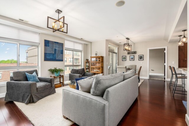 living room with visible vents, dark wood finished floors, baseboards, and a chandelier