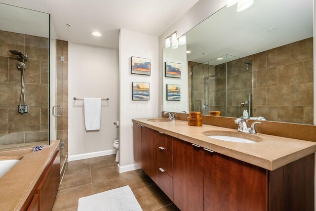 full bath with double vanity, tile patterned floors, a tile shower, and a sink