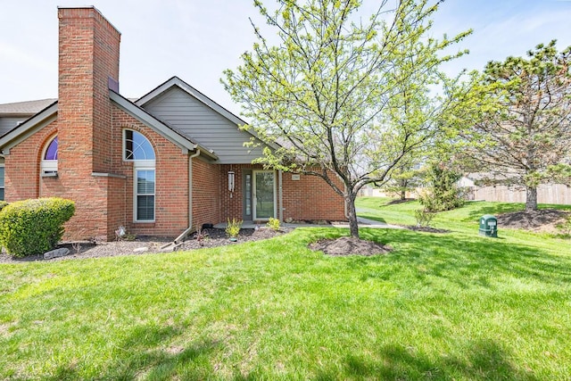 back of house featuring brick siding, a yard, and a chimney