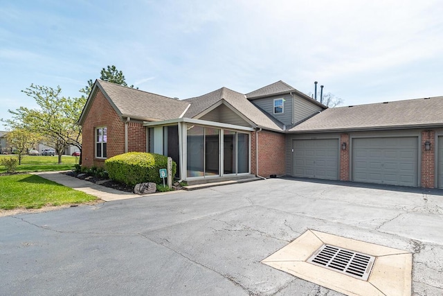 view of front of house with an attached garage, driveway, brick siding, and roof with shingles