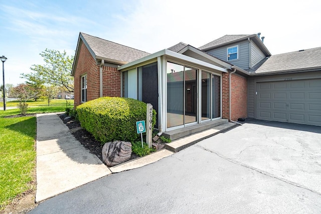 view of front of property featuring brick siding, an attached garage, and driveway
