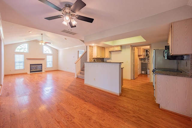 unfurnished living room featuring vaulted ceiling, visible vents, light wood-type flooring, a glass covered fireplace, and ceiling fan