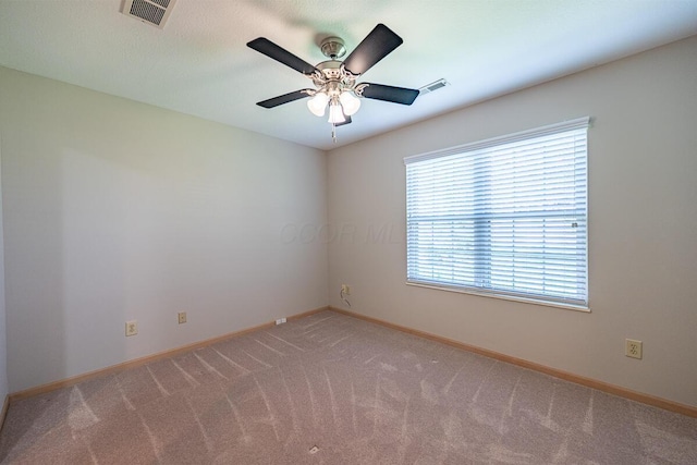 carpeted empty room featuring baseboards, a ceiling fan, and visible vents