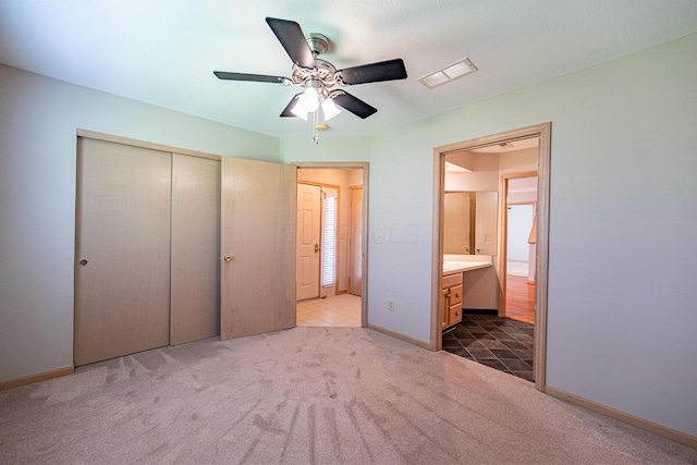 unfurnished bedroom featuring a closet, connected bathroom, carpet floors, baseboards, and visible vents