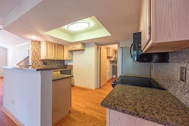 kitchen with a peninsula, light wood-type flooring, baseboards, decorative backsplash, and a raised ceiling