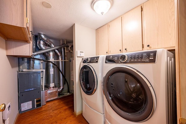 laundry room with wood finished floors, baseboards, washer and dryer, cabinet space, and a textured ceiling