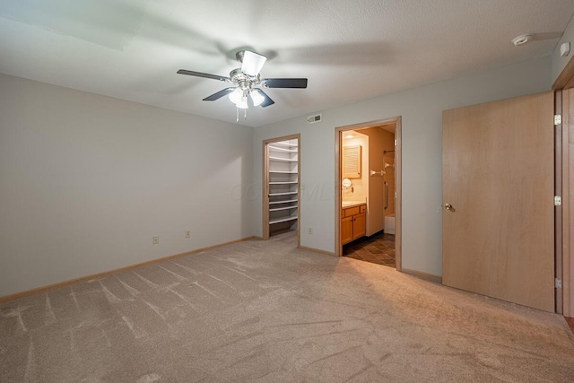 unfurnished bedroom featuring a spacious closet, baseboards, visible vents, and light colored carpet