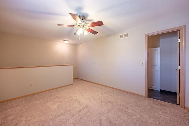 spare room featuring carpet floors, visible vents, a ceiling fan, and baseboards