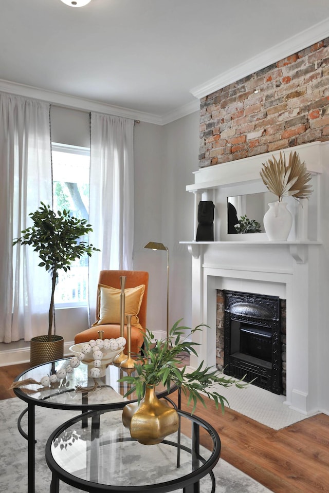 living area featuring wood finished floors, a large fireplace, and ornamental molding
