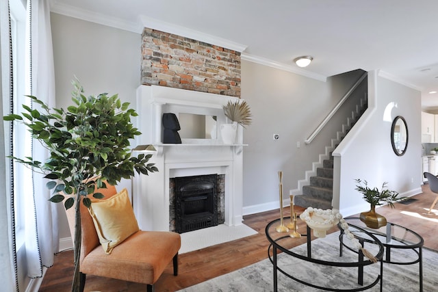 living room with crown molding, stairway, wood finished floors, and a fireplace with flush hearth