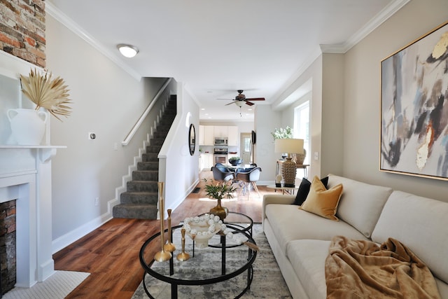 living room with crown molding, stairs, a fireplace with flush hearth, ceiling fan, and wood finished floors