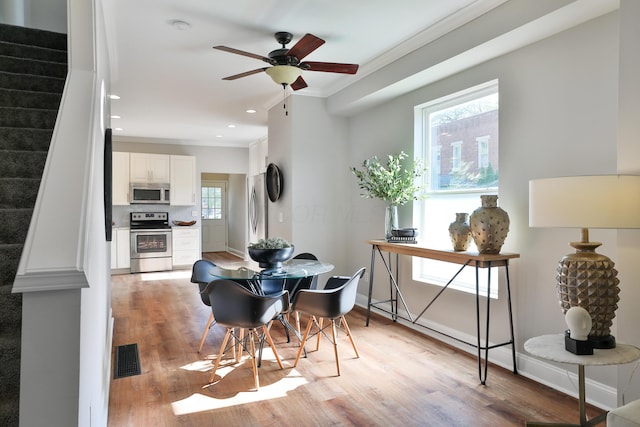 dining room featuring light wood-style flooring, a ceiling fan, ornamental molding, visible vents, and recessed lighting