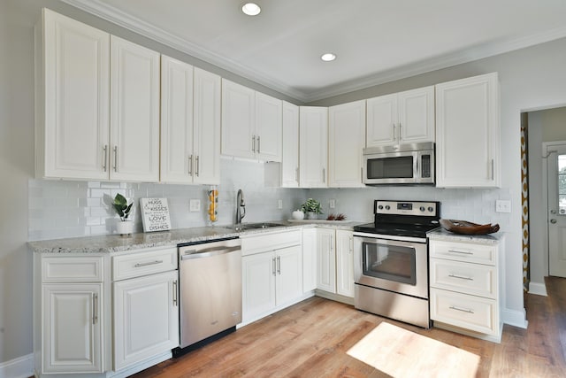 kitchen featuring backsplash, white cabinetry, stainless steel appliances, and a sink