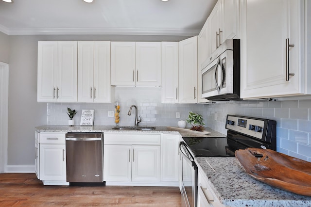 kitchen with light stone counters, a sink, ornamental molding, and appliances with stainless steel finishes