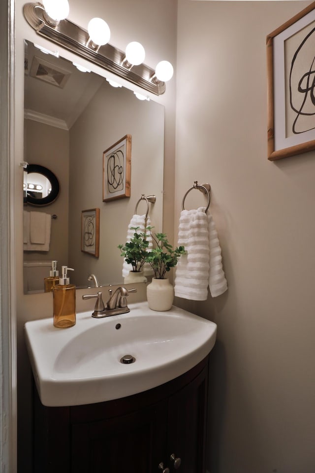 bathroom with crown molding, vanity, and visible vents