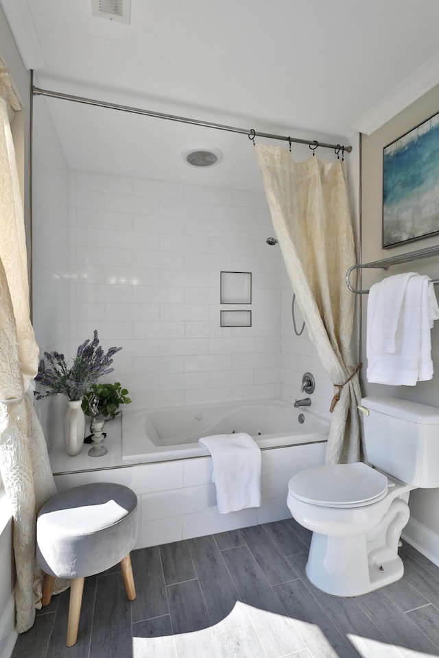 bathroom featuring visible vents, wood tiled floor, tiled shower / bath, and toilet