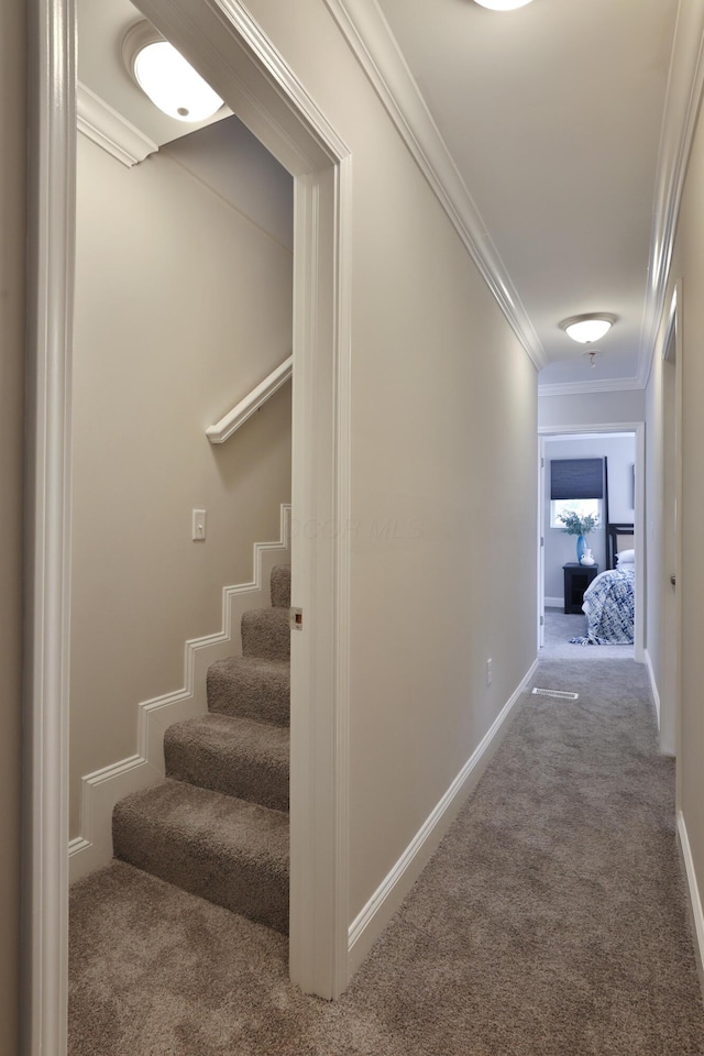 hallway featuring crown molding, carpet flooring, baseboards, and stairway