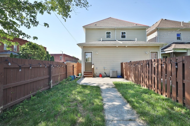 back of house featuring entry steps, a fenced backyard, central AC, and a yard