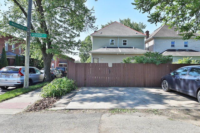 view of side of property with fence and a shingled roof