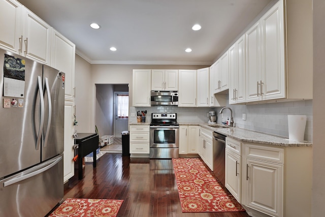 kitchen with stainless steel appliances, a sink, dark wood finished floors, decorative backsplash, and light stone counters