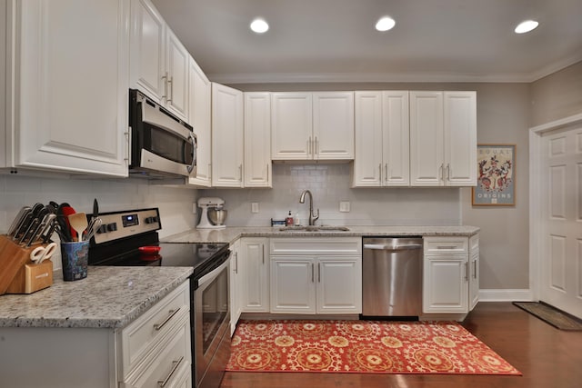 kitchen featuring a sink, dark wood finished floors, decorative backsplash, appliances with stainless steel finishes, and ornamental molding