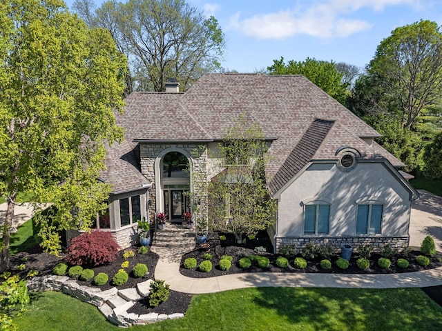 3906 Tarrington Ln, Columbus, OH 43220 - french country inspired facade featuring roof with shingles, stone siding, stucco siding, a front yard, and a chimney