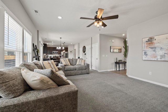 carpeted living room featuring recessed lighting, visible vents, baseboards, and ceiling fan with notable chandelier