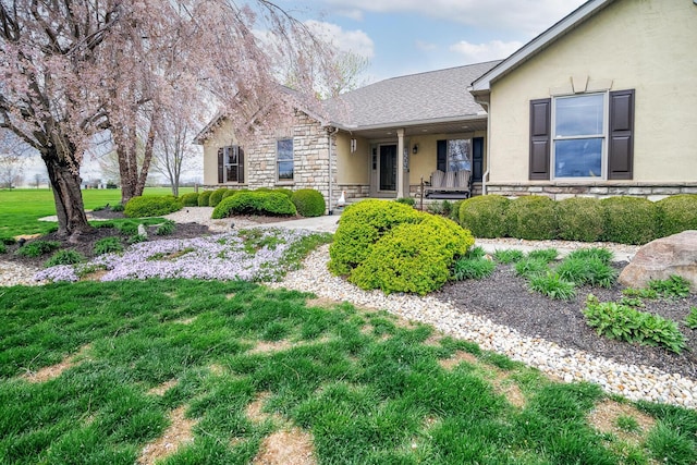 exterior space featuring stone siding, a front yard, and stucco siding