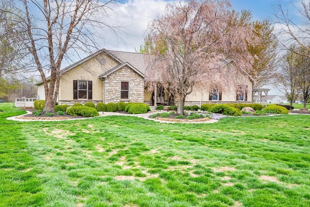 single story home featuring stucco siding, stone siding, and a front yard