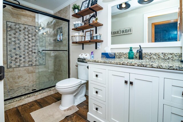 full bathroom featuring wood finished floors, a stall shower, vanity, toilet, and ornamental molding