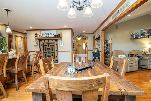 dining room with ornamental molding, a chandelier, and light wood-style flooring