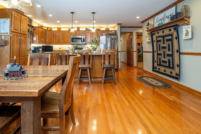 dining space featuring recessed lighting, light wood-style flooring, crown molding, and washer / clothes dryer