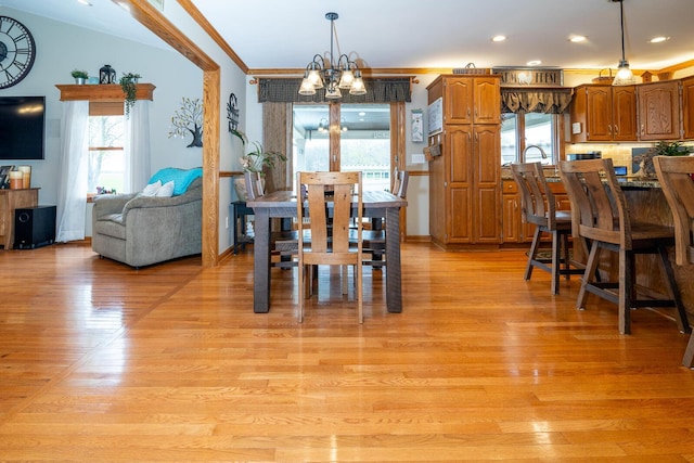 dining space with crown molding, a healthy amount of sunlight, a chandelier, and light wood-style flooring