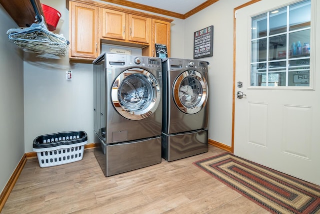 washroom featuring light wood finished floors, ornamental molding, washing machine and dryer, baseboards, and cabinet space