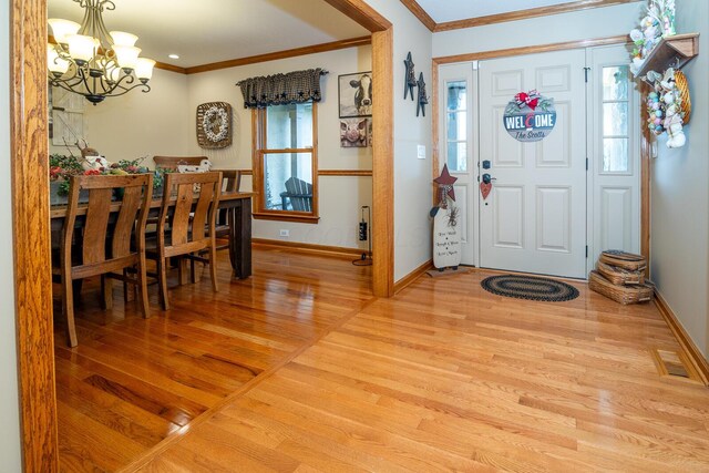 entryway with a notable chandelier, baseboards, ornamental molding, and wood finished floors