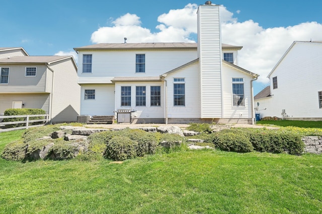 back of property with a chimney, fence, and a yard