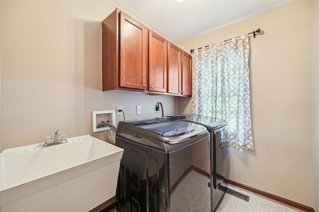 laundry area with a sink, a textured ceiling, washing machine and dryer, baseboards, and cabinet space
