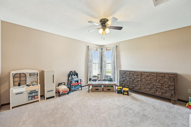 recreation room with carpet floors, a textured ceiling, and ceiling fan
