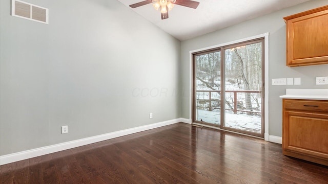 unfurnished dining area featuring dark wood-type flooring, vaulted ceiling, visible vents, and a ceiling fan
