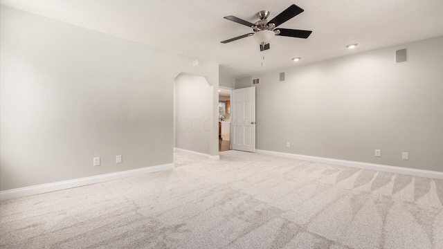 spare room featuring light colored carpet, baseboards, a ceiling fan, and visible vents
