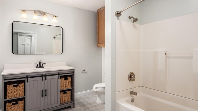 bathroom with wood finished floors, toilet, vanity, baseboards, and bathtub / shower combination