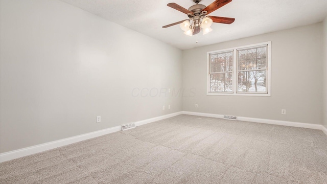 carpeted spare room featuring visible vents, a ceiling fan, and baseboards